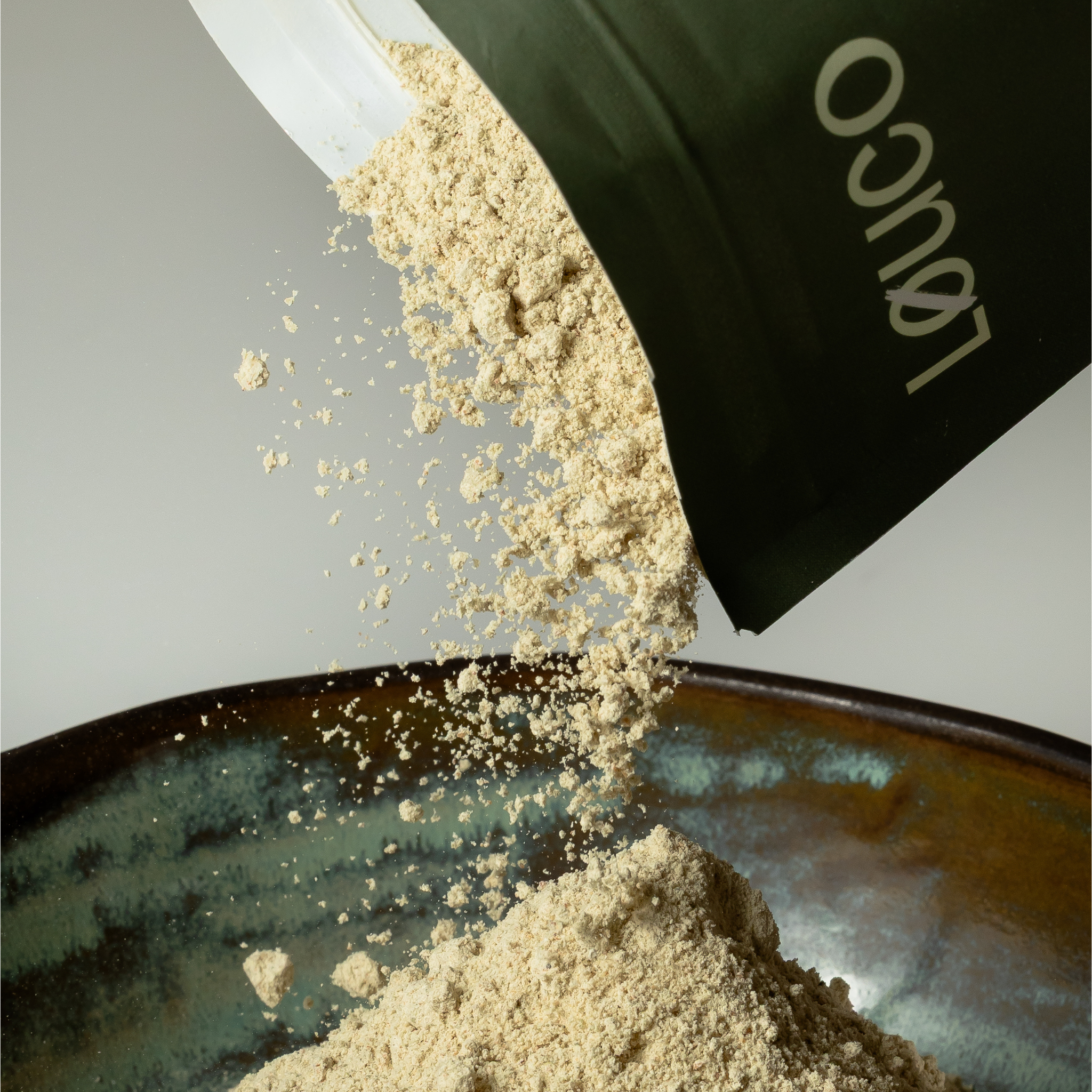LØUCO Protein Powder being poured into a bowl.