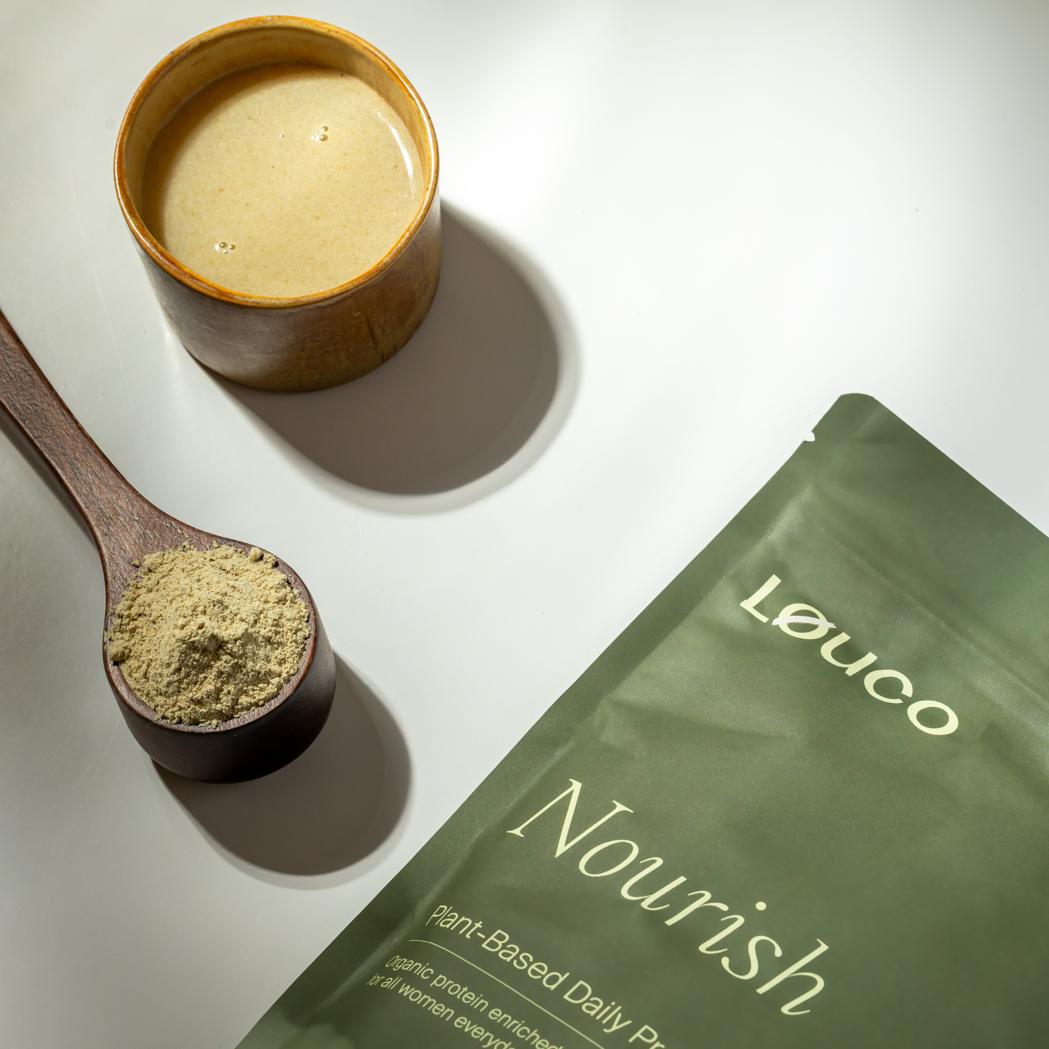 LØUCO Nourish plant-based daily protein packaging with a wooden spoon of powder and a protein shake of the product.
